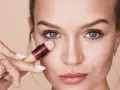Mujer aplicando corrector para maquillar bolsas ojos. Suave aplicador y piel radiante.