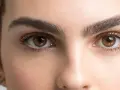 Ojos marrones y cejas pobladas, un ejemplo de cómo dar forma a las cejas para un look natural y definido.