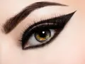 Ojo con maquillaje dramático, cejas definidas y un audaz delineado cat eye.
