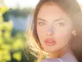 Rostro de mujer con cabello castaño y ojos verdes, iluminado por el sol. Su expresión transmite un glow up, un renacer radiante.
