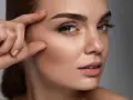 Primer plano de una mujer con cejas ascendentes, su mano tocando su sien.