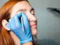 Manos enguantadas dibujan cejas a una mujer pelirroja. ¡No tengo cejas que puedo hacer!