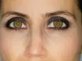 Ojos verdes con un intenso maquillaje negro, resaltando la mirada.