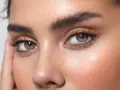 Ojos expresivos con pestañas largas y cejas perfectamente definidas tras un tratamiento de teñir cejas. Piel con pecas y rubor sutil.