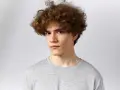Joven con un moderno corte de pelo rizado hombre, luciendo un estilo desenfadado y juvenil.