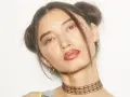Chica con peinados y maquillaje de los 90, dos moños altos, labios marrones y choker.