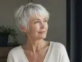 Mujer con pelo corto blanco moderno, sonríe mirando a la ventana.