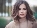 Mujer con peinados media melena elegantes, ondas suaves y un abrigo beige.