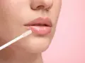 Labios brillantes y jugosos con un aplicador de gloss. El gloss da un acabado húmedo y voluminoso.