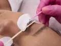 Manos enguantadas aplican producto para un lifting de pestañas, logrando un efecto espectacular sin inconvenientes.