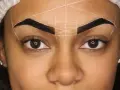 Ojos y cejas marcadas con líneas blancas para diseño. Se observa una posible alergia a la henna en las cejas.