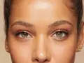 Primer plano de unos ojos verdes y marrones, mostrando cómo cambiar la forma de las cejas con maquillaje.