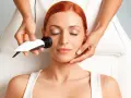 Mujer recibiendo tratamiento de radiofrecuencia facial. La cantidad de cuantas sesiones de radiofrecuencia facial son necesarias varía según el caso.