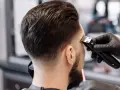 Barbero creando un tuper fade impecable en la nuca de un cliente.