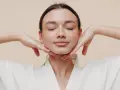 Mujer con ojos cerrados y manos en el rostro, practicando ejercicios faciales para flacidez cara.