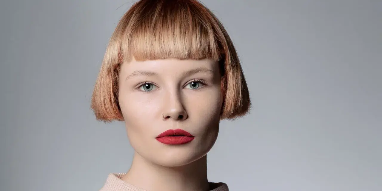 Mujer con pelo corto con flequillo desfilado, ojos azules y labios rojos.