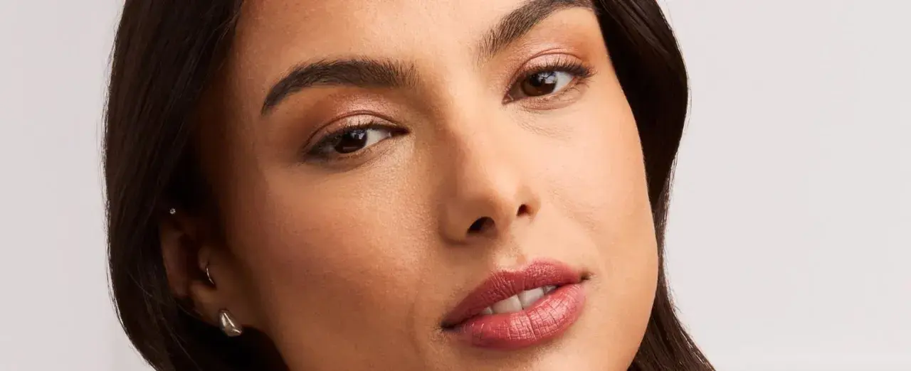 Rostro de mujer con un sutil maquillaje nude, resaltando sus ojos y labios con un toque natural y elegante.