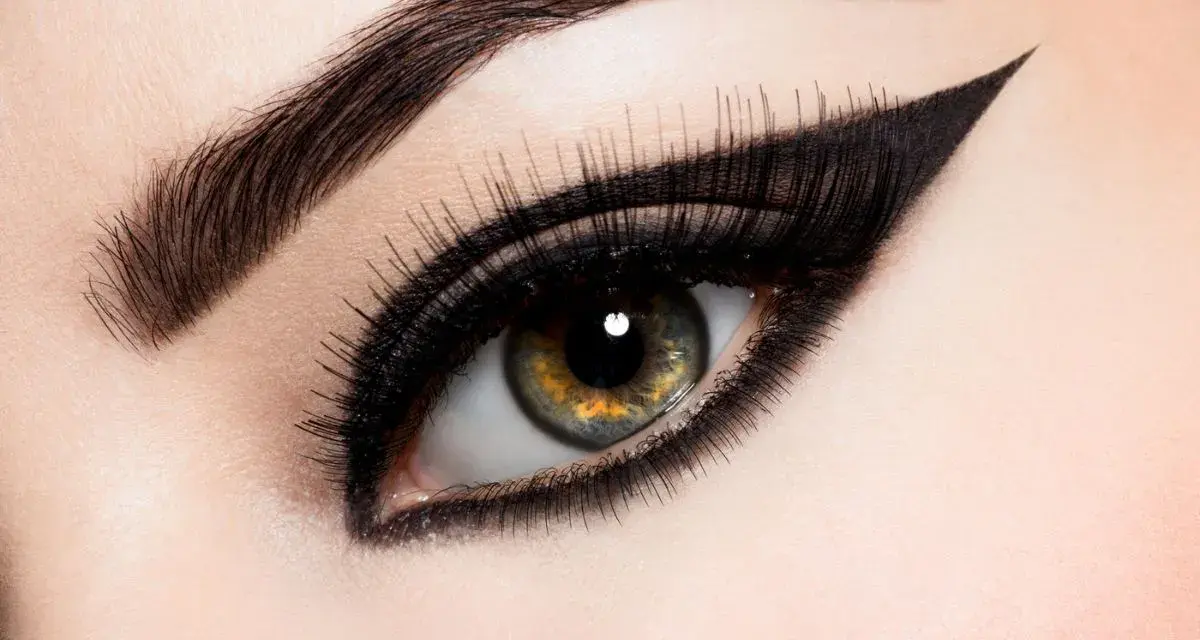 Ojo con maquillaje dramático, cejas definidas y un audaz delineado cat eye.