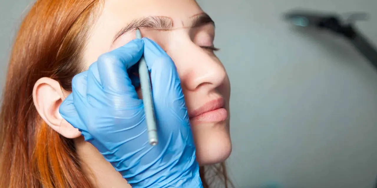 Manos enguantadas dibujan cejas a una mujer pelirroja. ¡No tengo cejas que puedo hacer!