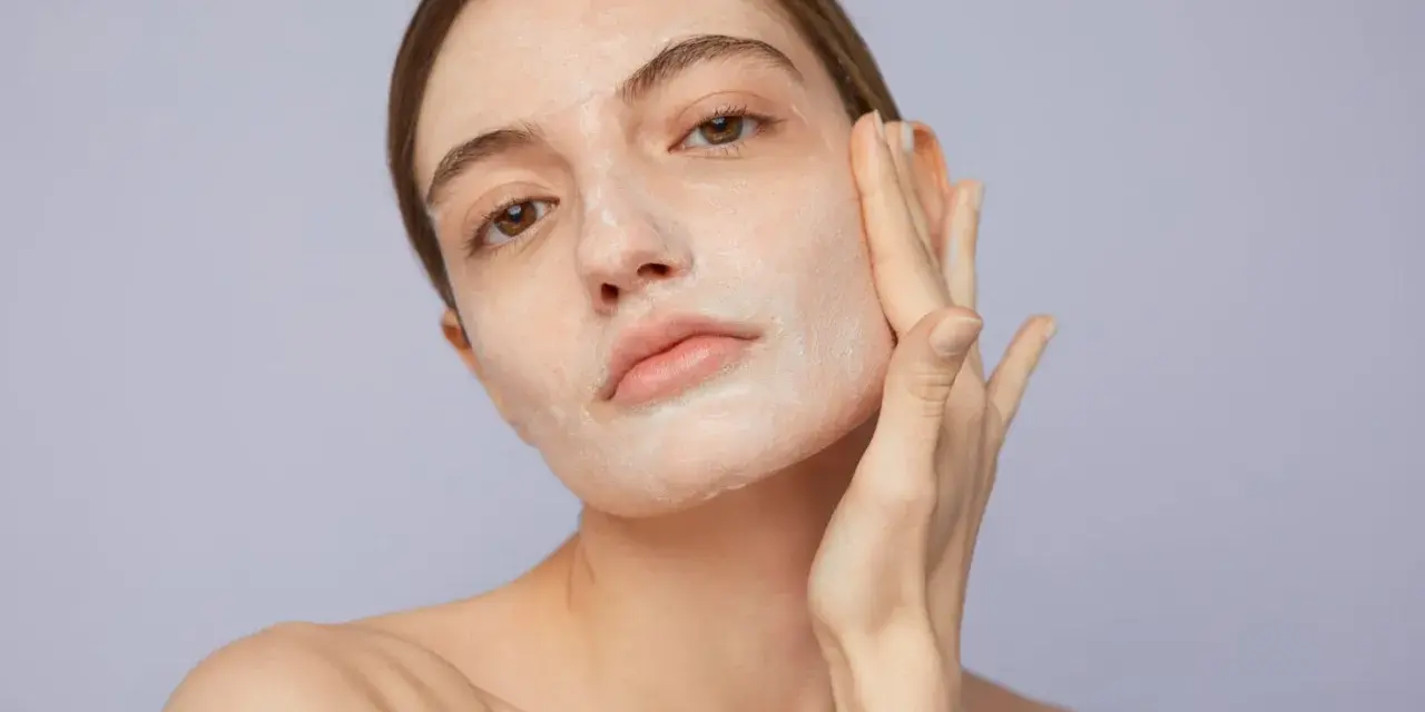 Mujer aplicándose crema para saber como exfoliar la piel. Suave masaje facial para una piel radiante.