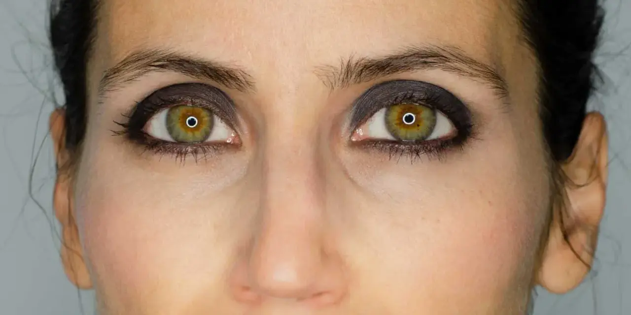 Ojos verdes con un intenso maquillaje negro, resaltando la mirada.