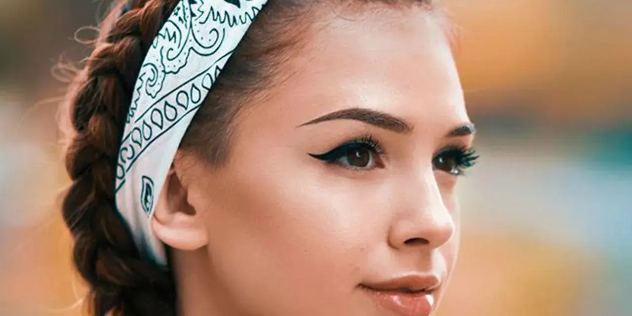 Chica con trenzas y pañuelo, mostrando cómo pintar la raya del ojo con delineado cat eye perfecto.