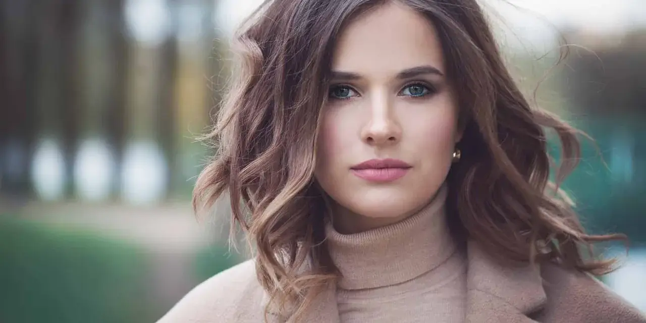 Mujer con peinados media melena elegantes, ondas suaves y un abrigo beige.