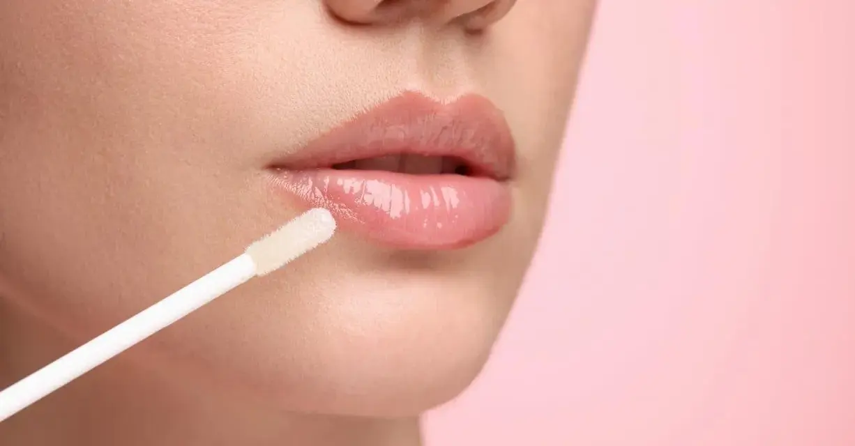 Labios brillantes y jugosos con un aplicador de gloss. El gloss da un acabado húmedo y voluminoso.