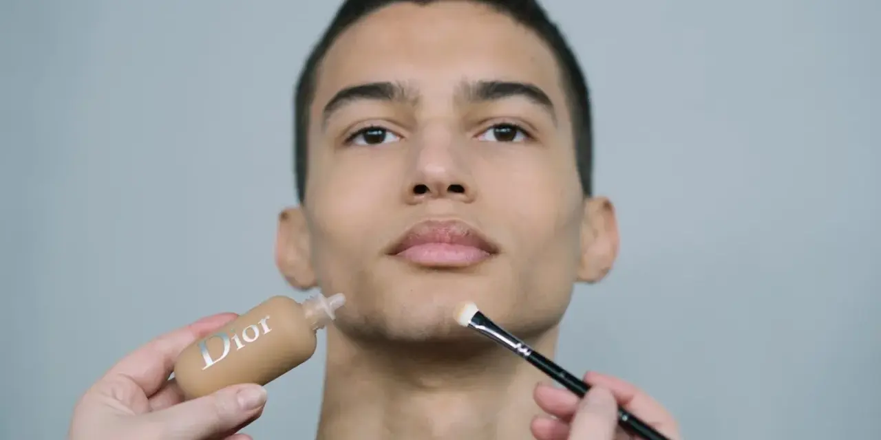 Aplicación de maquillaje hombre con base Dior y brocha.