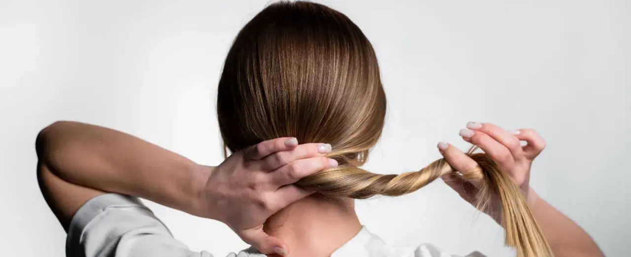 Manos trenzando el cabello, un peinado sencillo para dormir que protege tu melena.