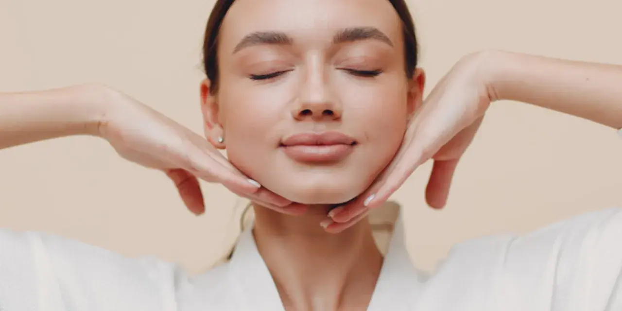 Mujer con ojos cerrados y manos en el rostro, practicando ejercicios faciales para flacidez cara.
