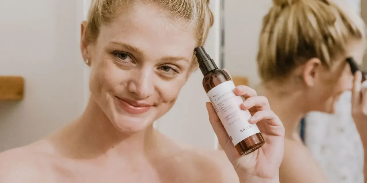 Mujer sonriente aplica bruma facial para como fijar el maquillaje. El producto es de la marca KÁLOS.
