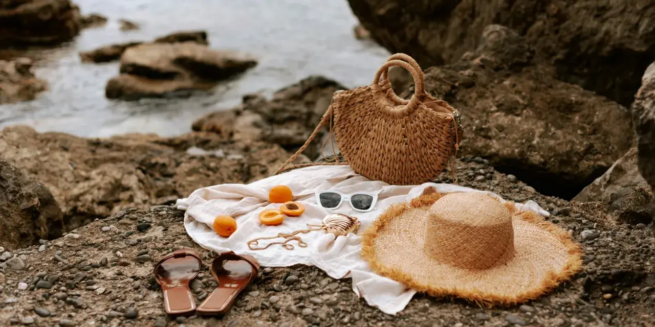 Accesorios de playa: sombrero, bolso, chanclas, gafas de sol y albaricoques, ideales para saber como mantener el moreno de playa.