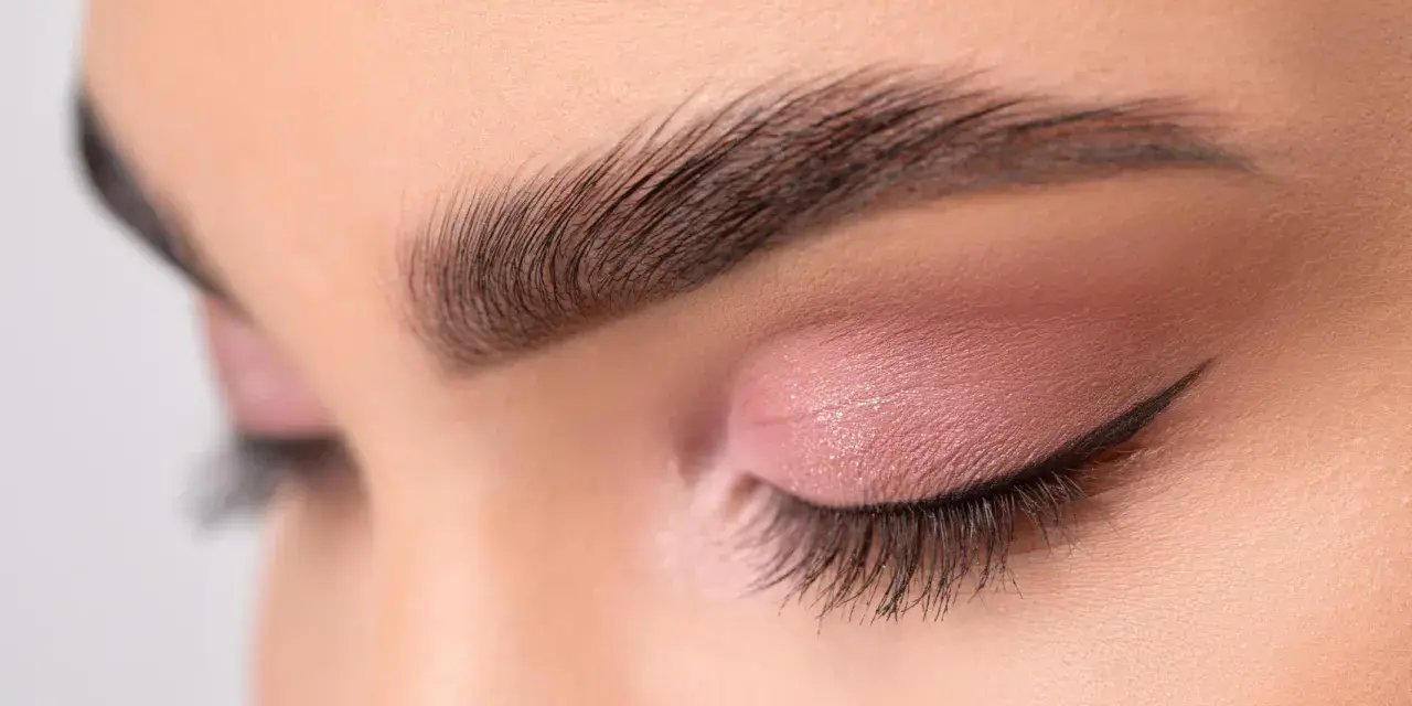 Ojo cerrado con sombra rosa, delineado cat eye y cejas separadas bien definidas.