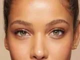 Primer plano de unos ojos verdes y marrones, mostrando cómo cambiar la forma de las cejas con maquillaje.