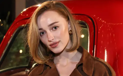 Primer plano de una mujer con maquillaje natural, destacando las partes de las cejas y un labial nude, frente a un vehículo rojo brillante.