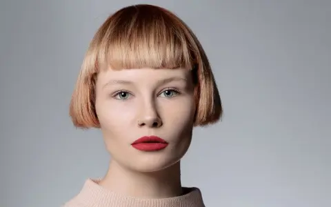 Mujer con pelo corto con flequillo desfilado, ojos azules y labios rojos.