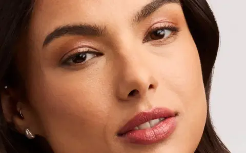 Rostro de mujer con un sutil maquillaje nude, resaltando sus ojos y labios con un toque natural y elegante.
