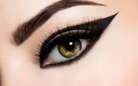 Ojo con maquillaje dramático, cejas definidas y un audaz delineado cat eye.