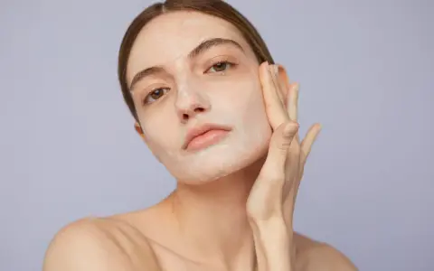 Mujer aplicándose crema para saber como exfoliar la piel. Suave masaje facial para una piel radiante.