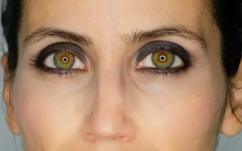 Ojos verdes con un intenso maquillaje negro, resaltando la mirada.