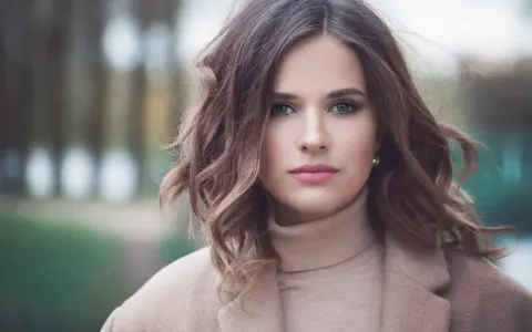 Mujer con peinados media melena elegantes, ondas suaves y un abrigo beige.