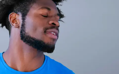 Hombre con perilla barba y ojos cerrados, disfrutando un momento de paz.