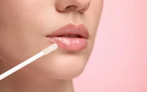 Labios brillantes y jugosos con un aplicador de gloss. El gloss da un acabado húmedo y voluminoso.