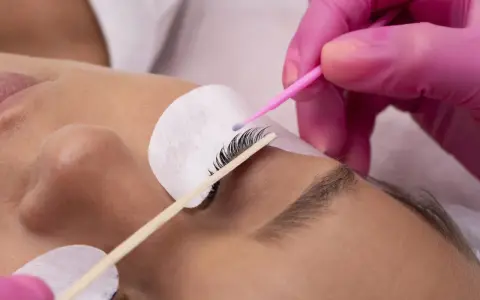 Manos enguantadas aplican producto para un lifting de pestañas, logrando un efecto espectacular sin inconvenientes.