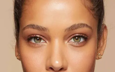 Primer plano de unos ojos verdes y marrones, mostrando cómo cambiar la forma de las cejas con maquillaje.