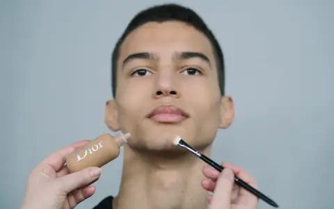 Aplicación de maquillaje hombre con base Dior y brocha.
