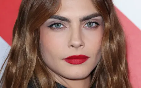 Primer plano de una mujer con cejas pobladas y labios rojos. ¿Recortar cejas sí o no? La decisión es tuya.