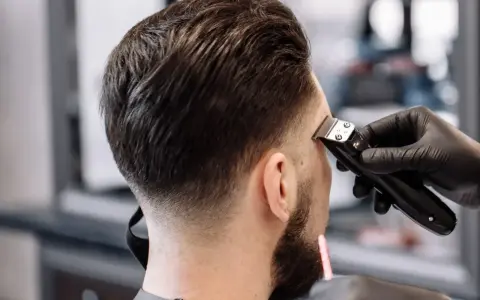 Barbero creando un tuper fade impecable en la nuca de un cliente.