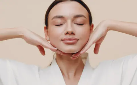 Mujer con ojos cerrados y manos en el rostro, practicando ejercicios faciales para flacidez cara.